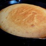 black skillet with cornbread with golden top