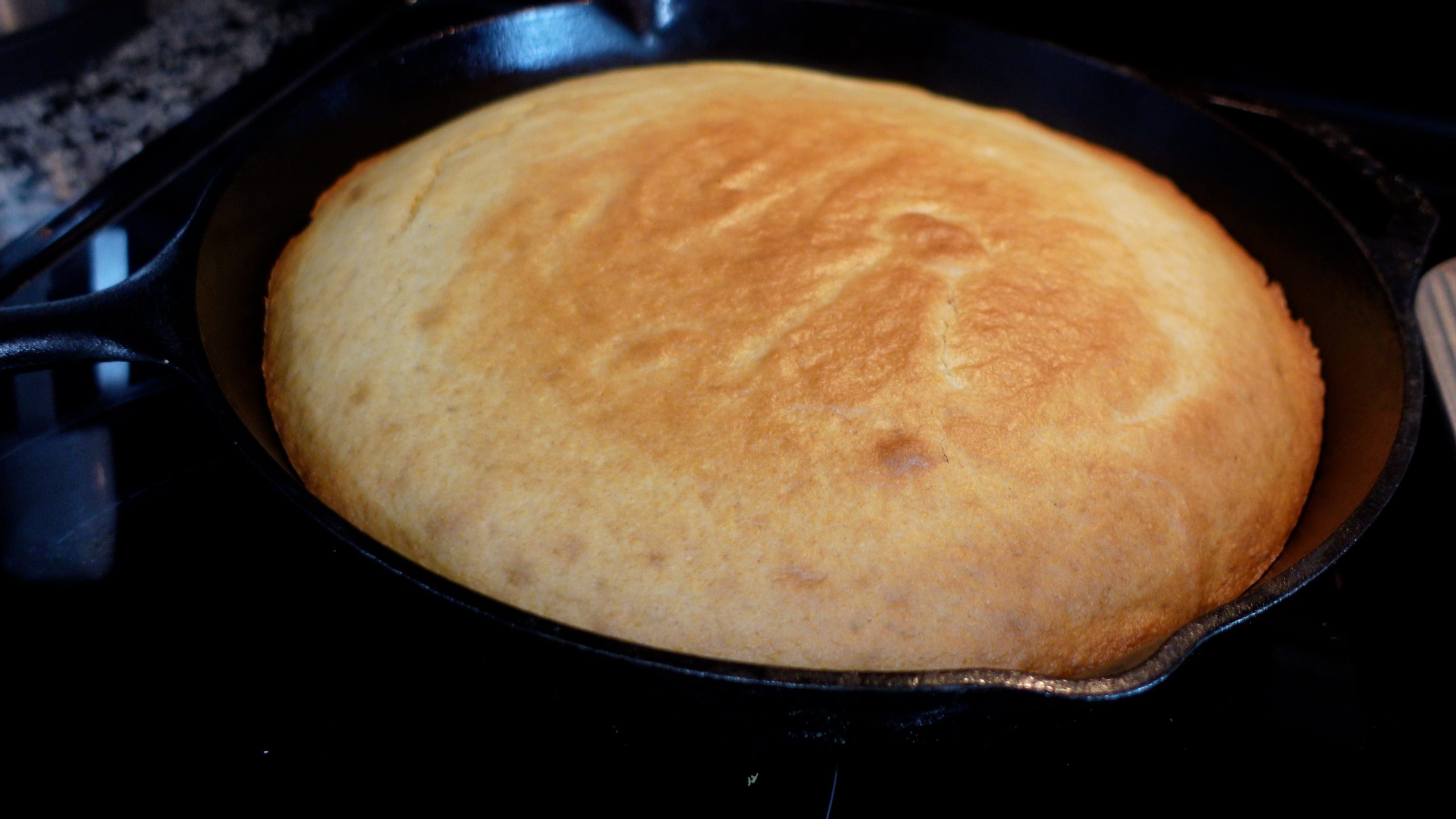 black skillet with cornbread with golden top