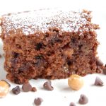 brownie sprinkled with white powdered sugar on white plate with chocolate chips