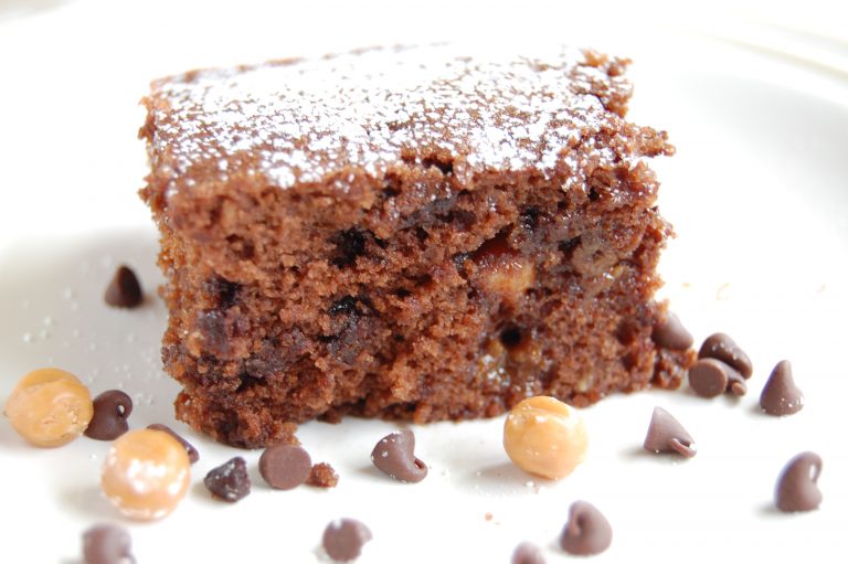 brownie sprinkled with white powdered sugar on white plate with chocolate chips