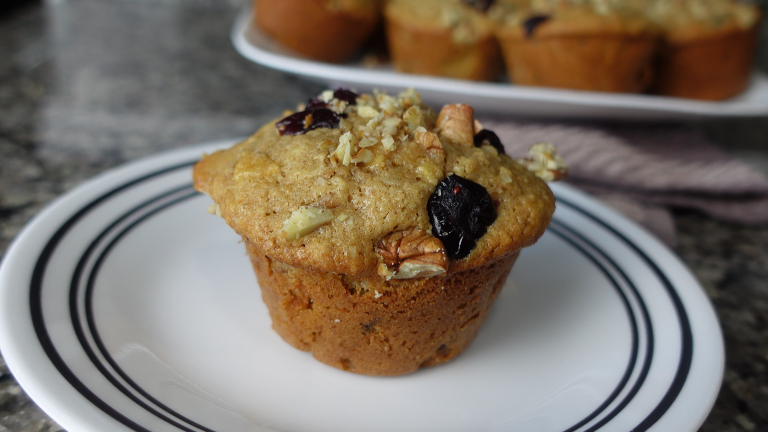 muffin topped with cranberries and pecans on a white plate